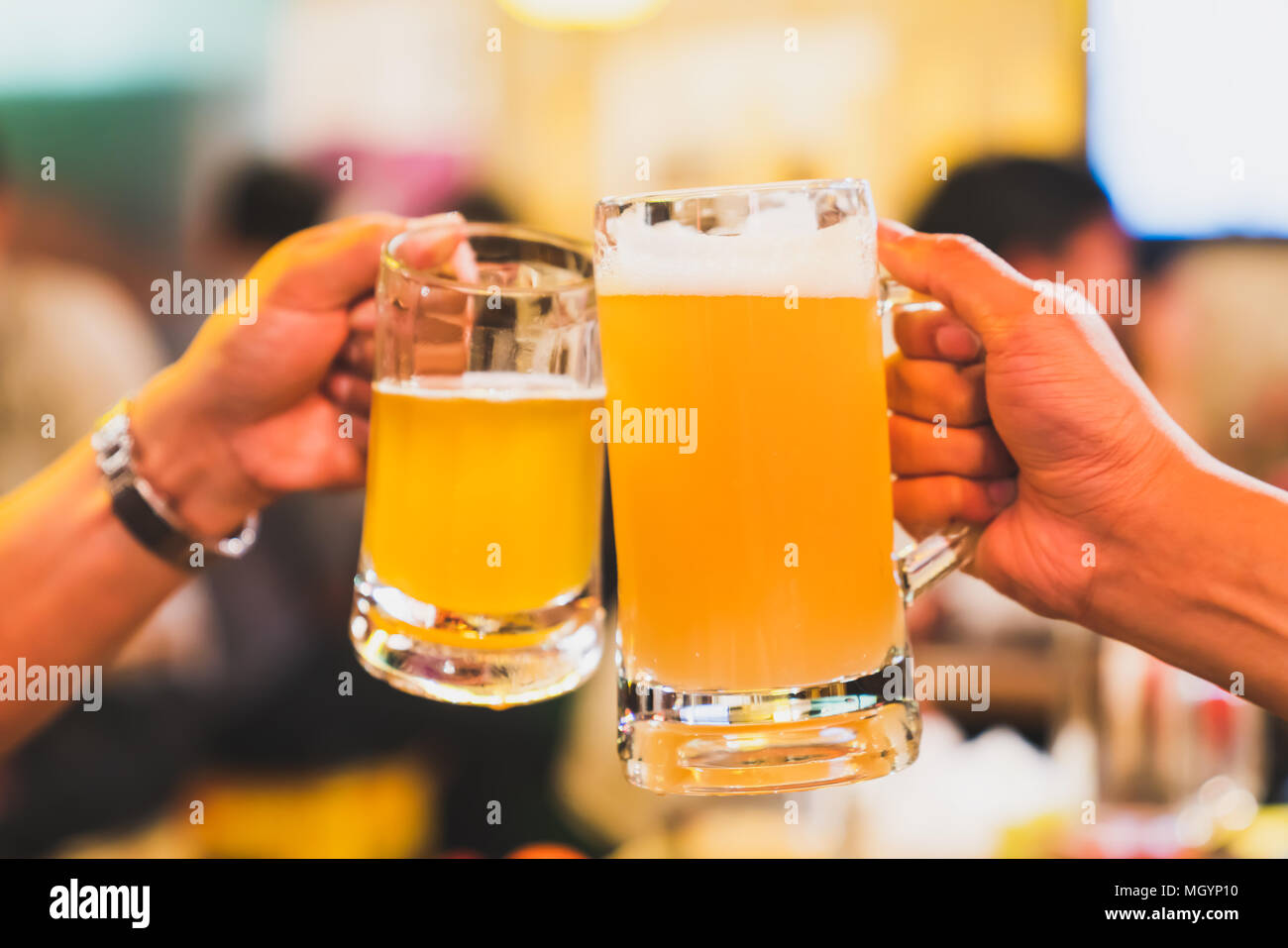 Gli amici o i colleghi di lavoro il tifo con birra, celebrando insieme al ristorante o night club. I giovani la tostatura in evento di festa dopo il lavoro Foto Stock