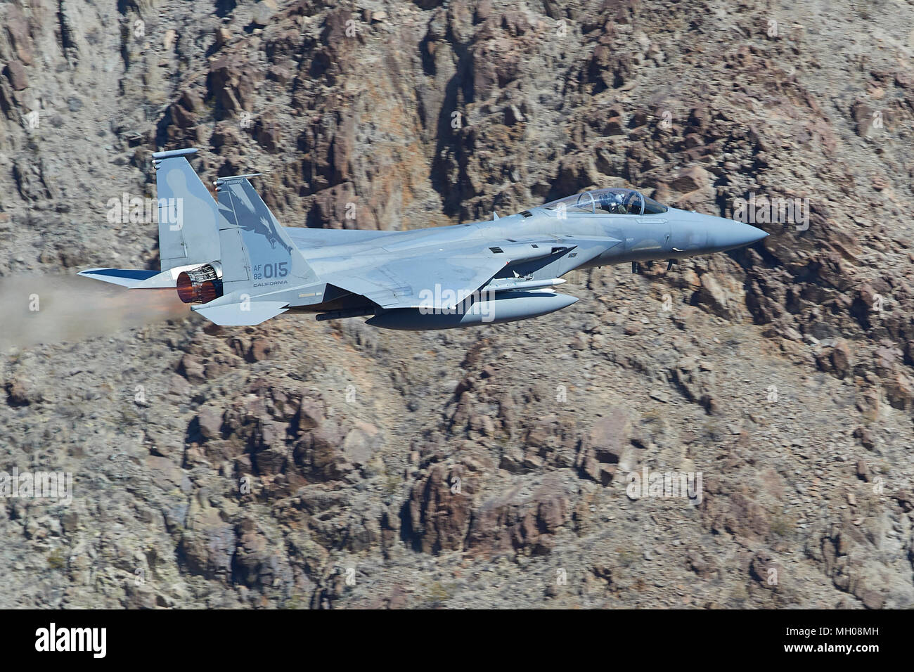 Close up, vista di profilo di un F-15C Eagle jet fighter, Afterburner acceso, volare a livello basso attraverso il Rainbow Canyon, California, USA. Foto Stock