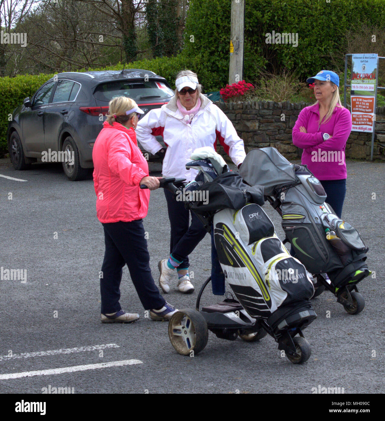 3 di mezza età golfisti femmina riuniti nel club car park con la loro golf club e trollies. Foto Stock