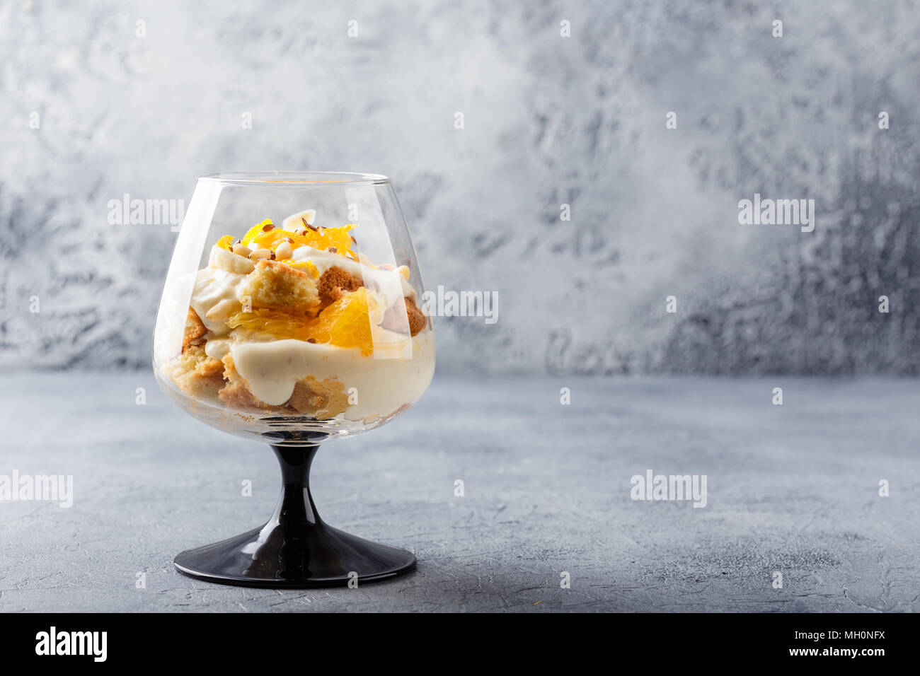 Vetro con una sana in casa dessert stratificata scherzare con Orange, biscotti, yogurt e cereali Foto Stock