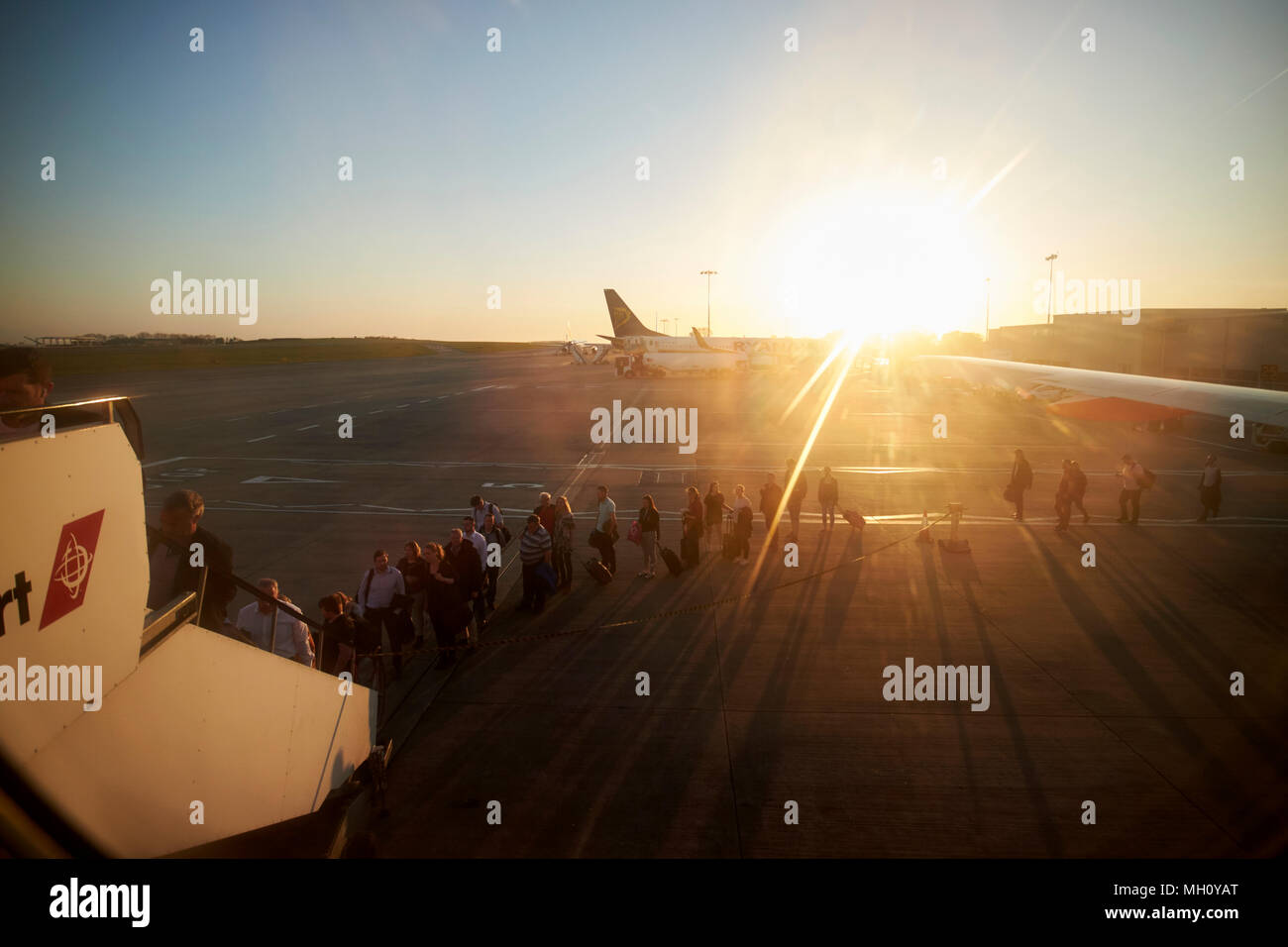 I passeggeri di salire a bordo a tarda sera volo Easyjet aereo tramite la parte posteriore passi presso l'aeroporto di Bristol al tramonto England Regno Unito Foto Stock