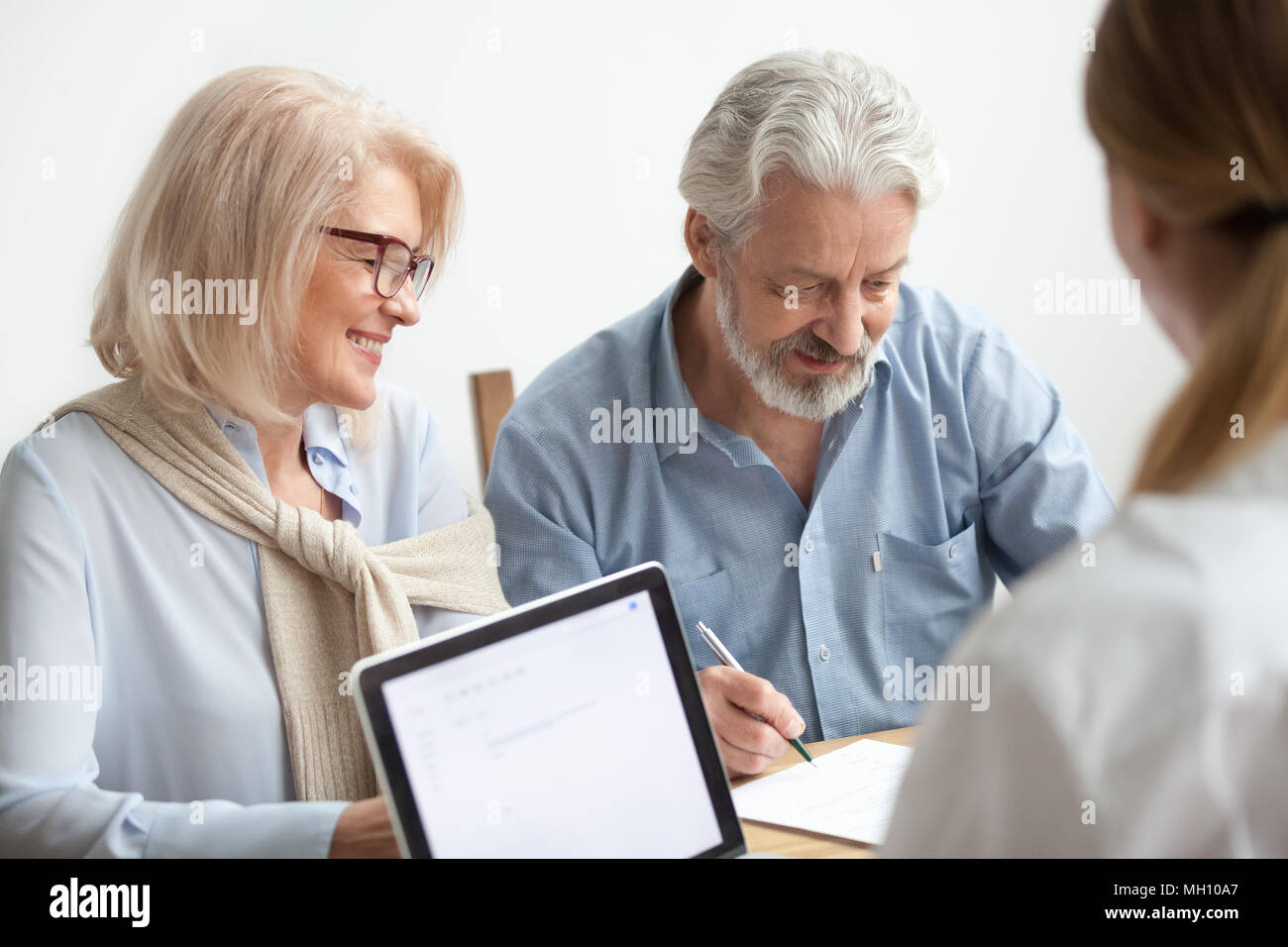 Felice coppia senior firma documento alla riunione con una finanziaria Foto Stock