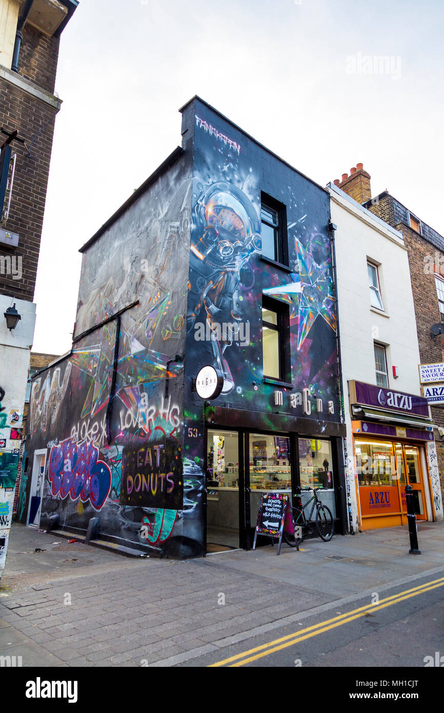 Edificio coperto di street art graffiti, facciata di Magna donut shop in Brick Lane, London, Regno Unito Foto Stock