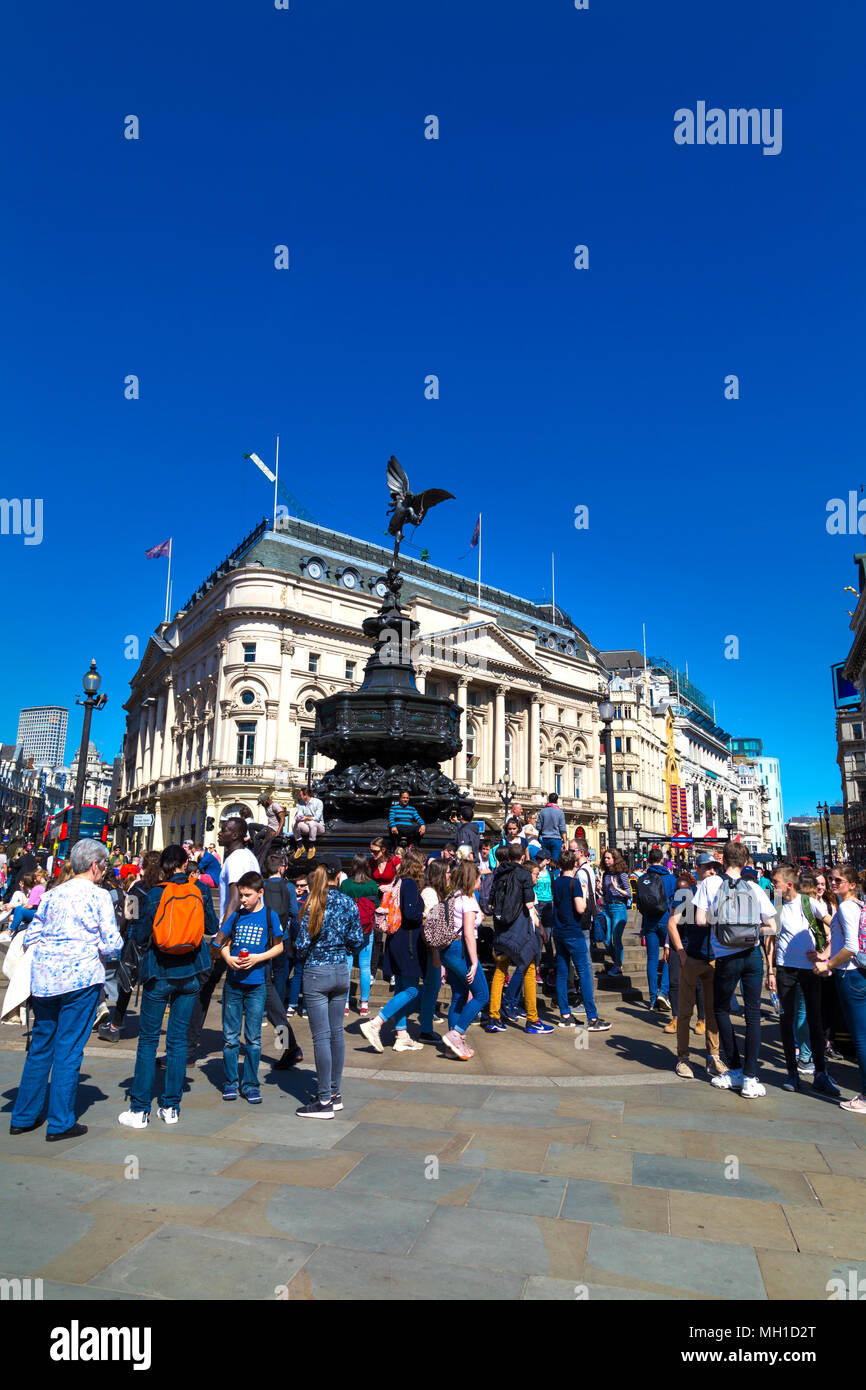 Piazza trafficata - i turisti a piedi a Piccadilly Circus e seduta sulle fasi di Shaftesbury Memorial Fountain, London, Regno Unito Foto Stock