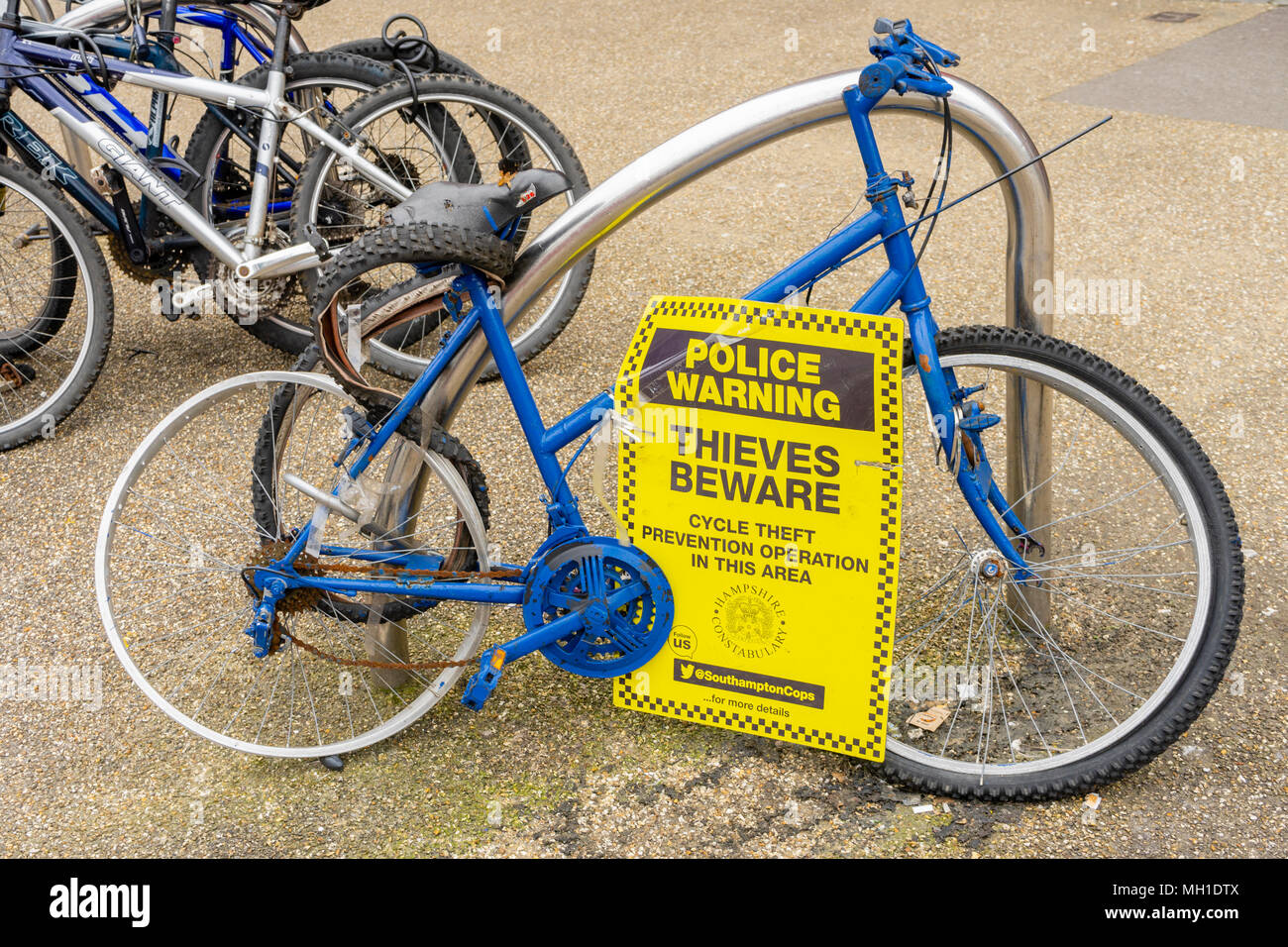 Bici blu disonorata in mostra in una strada, la polizia di Hampshire Constabulary che emette un avvertimento su un segno 'ladri attenzione', Inghilterra, Regno Unito Foto Stock
