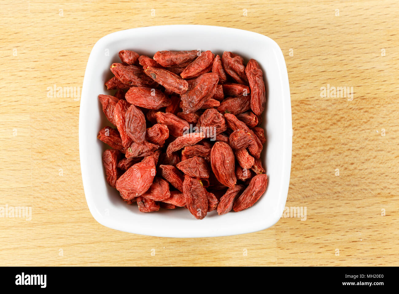Essiccati goji bacche in un recipiente su un tagliere di legno. Foto Stock