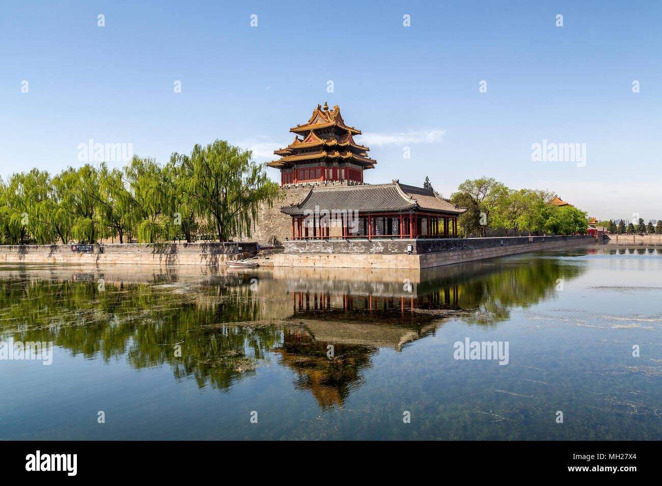 Angolo nord-est la Torre della Città Proibita di Pechino, Cina. Un riflesso della torre e gli alberi di salice può essere visto nel fossato che circonda la città. Foto Stock