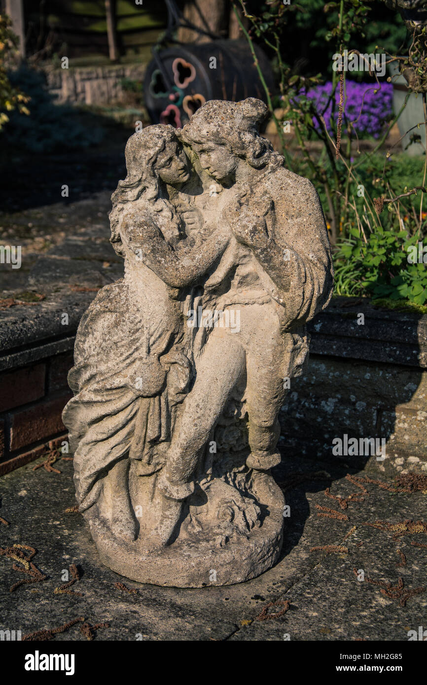 Giardino Classico statua di Romeo e Giulietta abbracciano l un l altro. Tipicamente si trova nei giardini alto-basso del Regno Unito. In calcestruzzo. Splendidamente weathered. Foto Stock