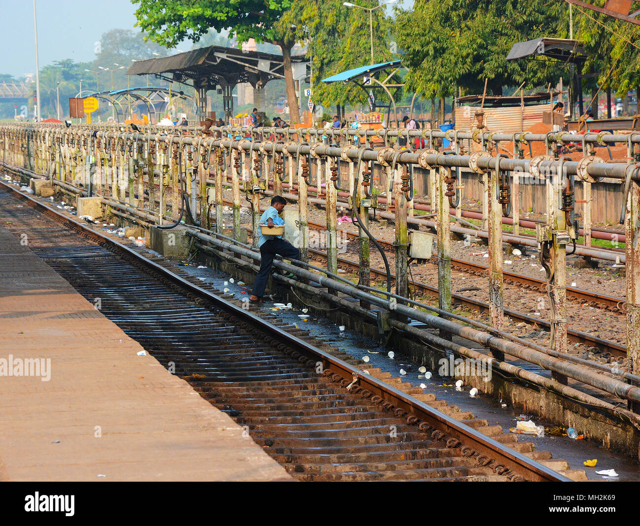 L'uomo attraversando i binari ferroviari alla stazione di Margao, vicino Benaulim, Goa, India Foto Stock