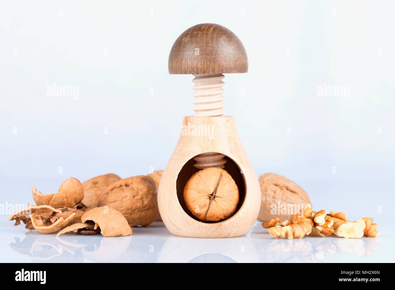 Una noce schiaccianoci con split noci isolati su sfondo bianco e con la riflessione in terra. Foto Stock