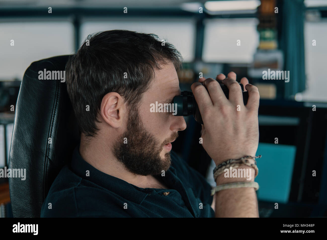 Deck ufficiale di navigazione sul ponte di navigazione. Egli guarda attraverso il binocolo Foto Stock