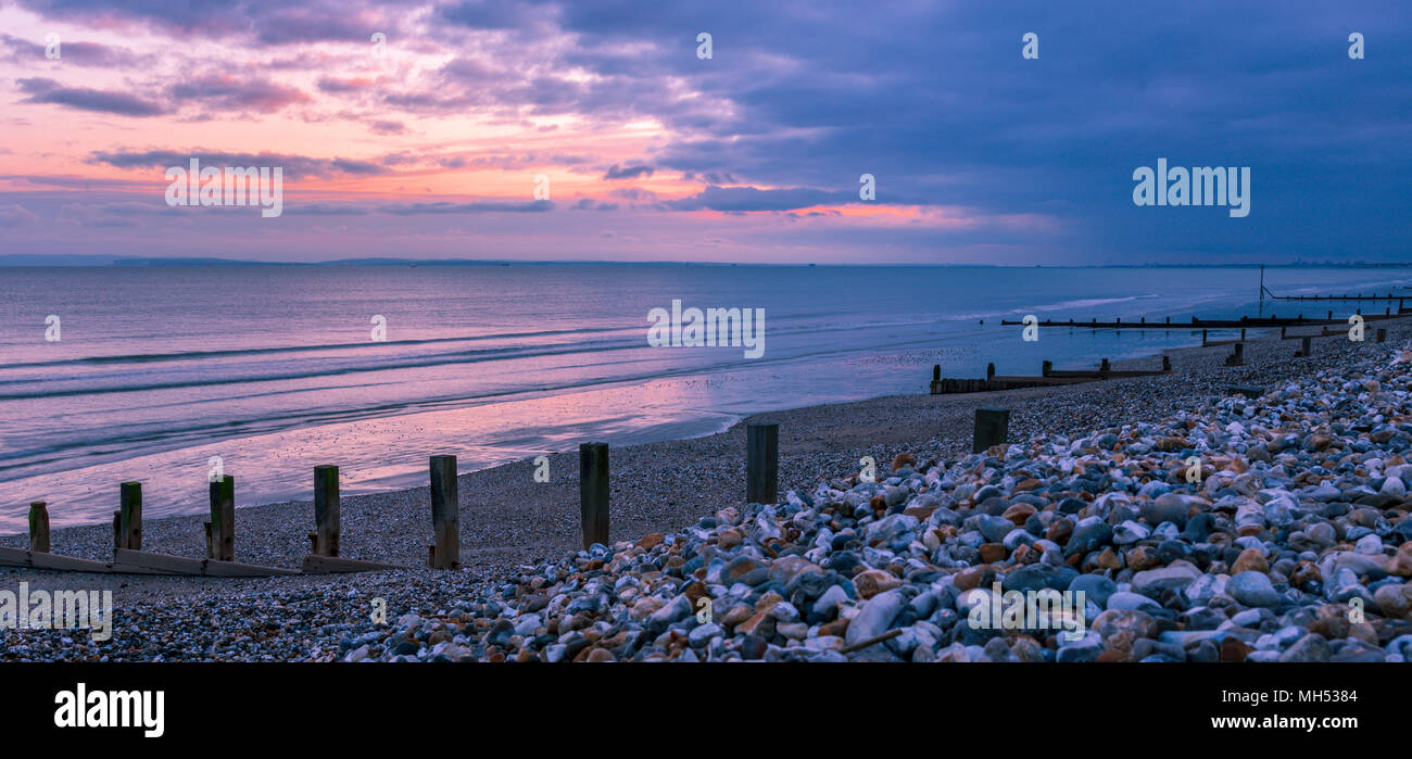Tramonto, pennelli e sagome a est Wittering litorale, Inghilterra, Regno Unito. Foto Stock