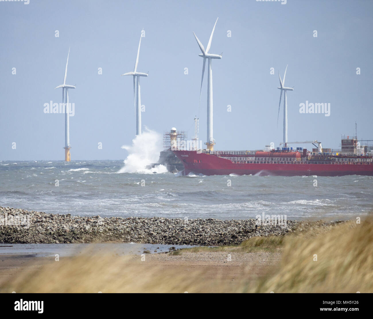 Nave che parte verso il mare da Tees, estuario di Teesmouth in una giornata di tempesta. Parco eolico di Redcar offshore, turbine eoliche in background. Teesmouth, Inghilterra. REGNO UNITO Foto Stock