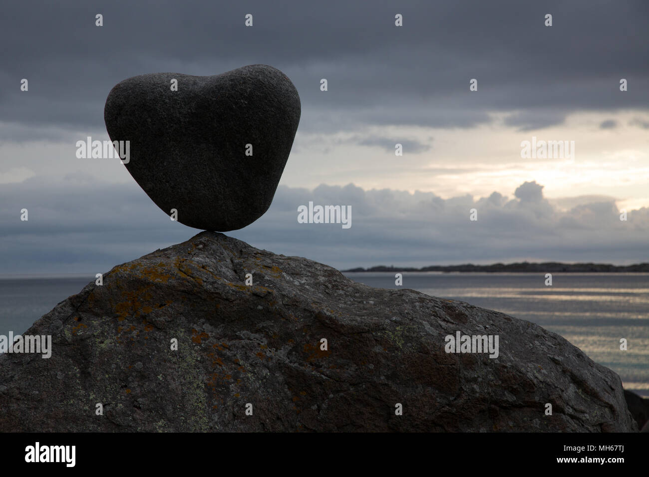 A forma di cuore ad rock equilibrata su un masso Foto Stock