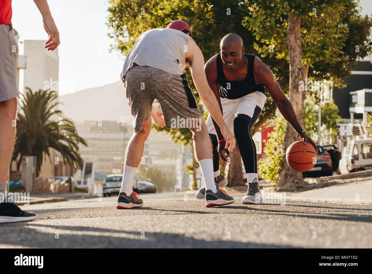 Gli uomini la riproduzione di gioco di basket in una giornata di sole su una strada vuota. Gli uomini praticano la pallacanestro talento nel dribbling sulla strada. Foto Stock