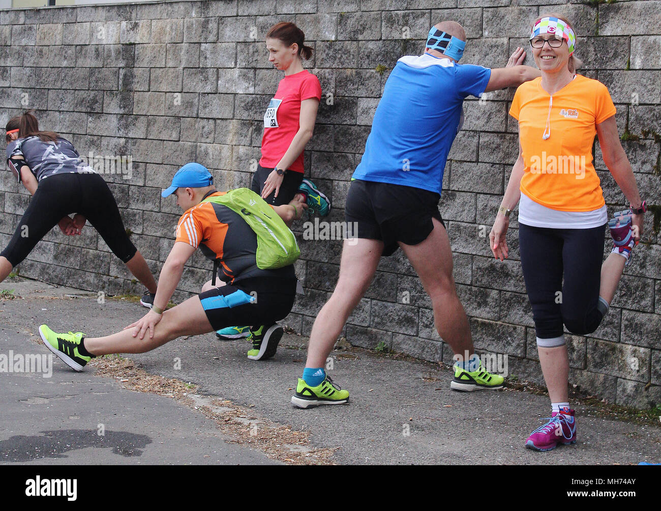 Guide di scorrimento a fare stretching prima di iniziare una maratona - attivo montare le persone Foto Stock