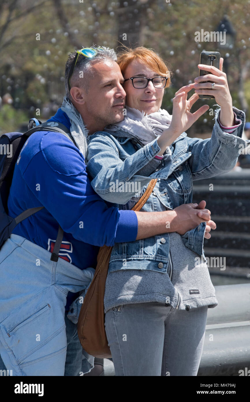 Una coppia sposata a Washington Square Park prendendo un selfie in una felice posa affettuoso. In Greenwich Village, Manhattan, New York City. Foto Stock