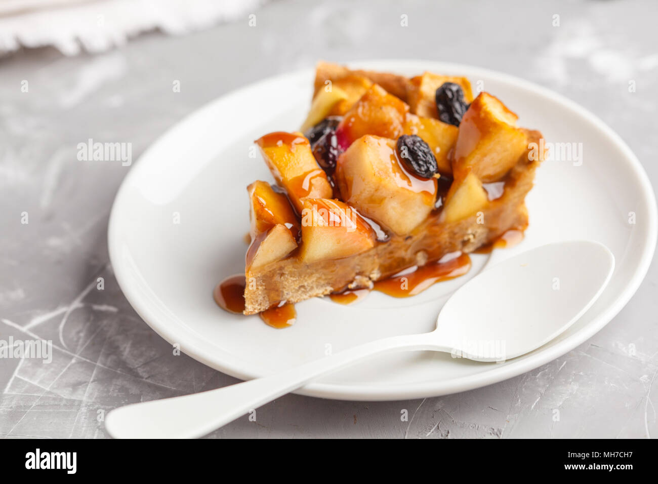 Pezzo di vegan la torta di mele con cannella e uvetta e caramello, uno sfondo grigio. Foto Stock