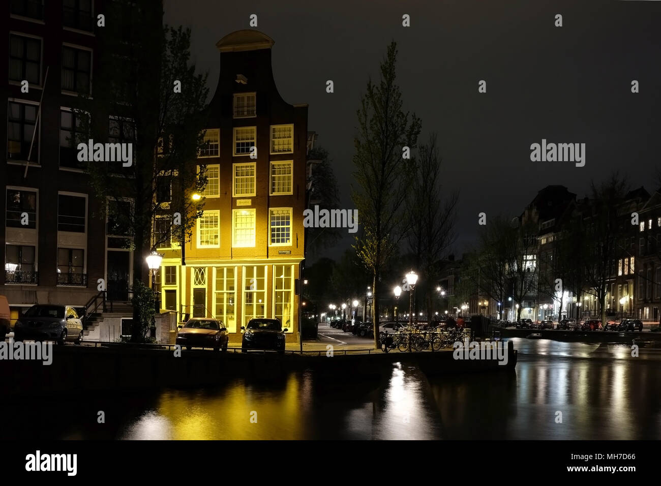 Notte a Amsterdam: edificio illuminato vicino al fiume canal con la riflessione sull'acqua Foto Stock