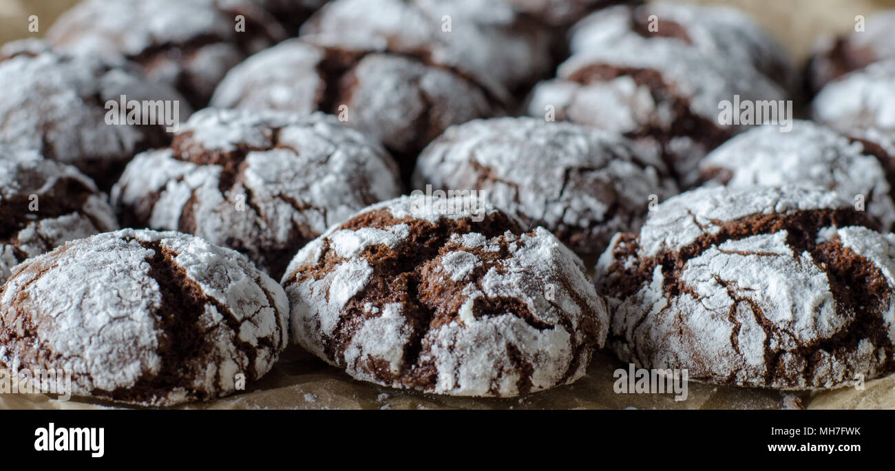 Chocolate crinkle cookies con polvere di glassa di zucchero. Incrinato biscotti al cioccolato su sfondo della carta. close up. vista laterale Foto Stock