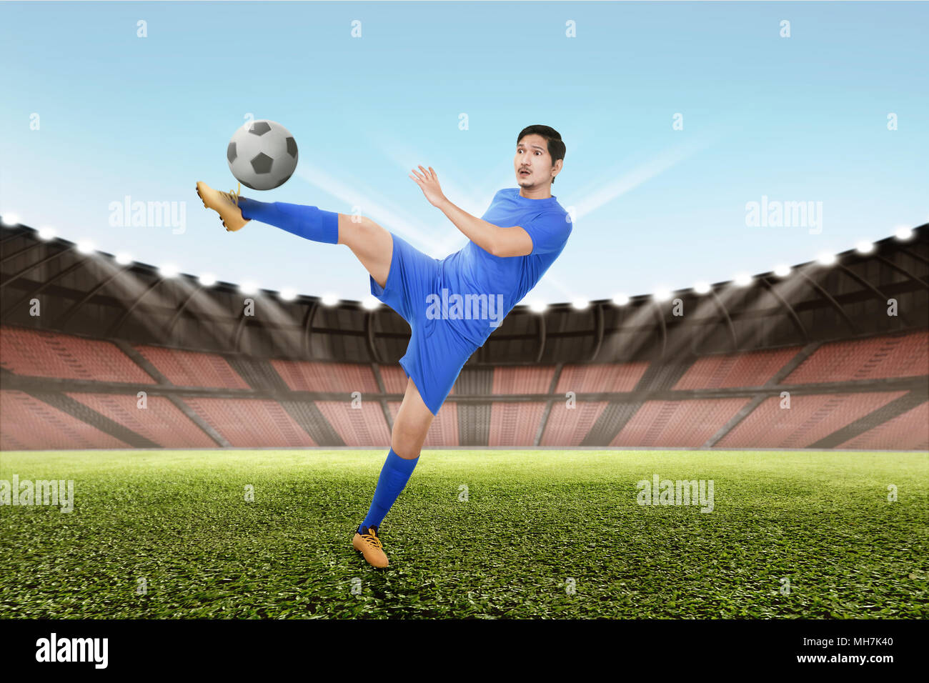 Strong asian giocatore di calcio calciare la palla sul campo Foto Stock