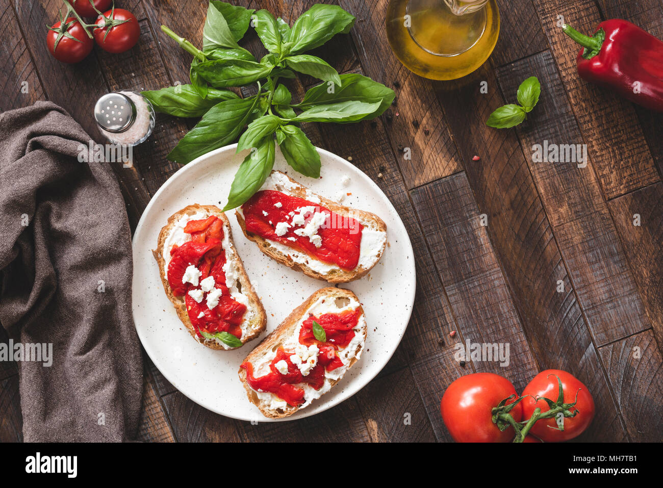 Italian Bruschetta con peperoni arrostiti, il formaggio feta e olio d'oliva sul vecchio tavolo in legno. Vista da sopra con copia spazio per il testo Foto Stock