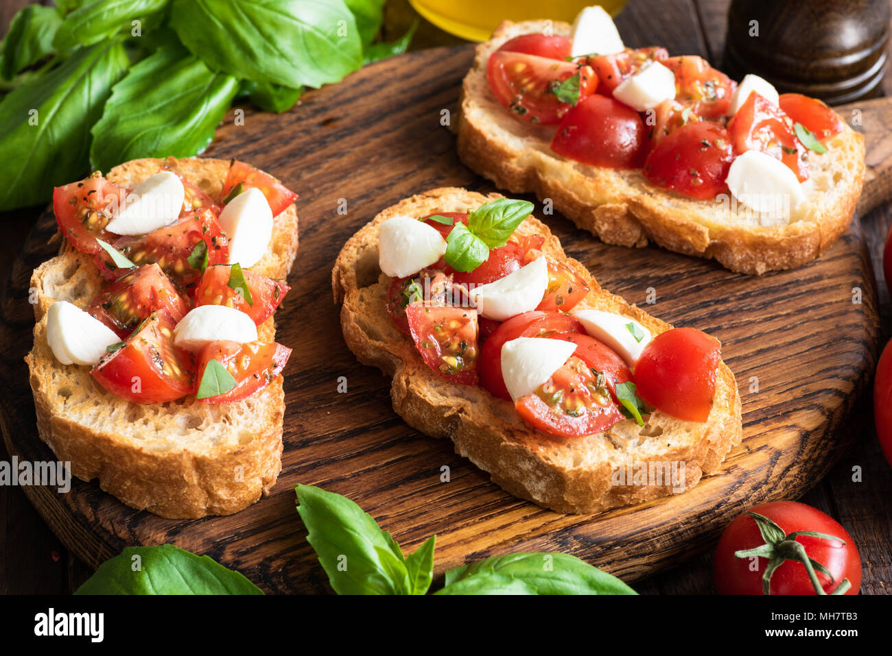 Italian bruschette o Crostini con pomodoro e mozzarella basilico sul tagliere di legno. Primo Piano Foto Stock