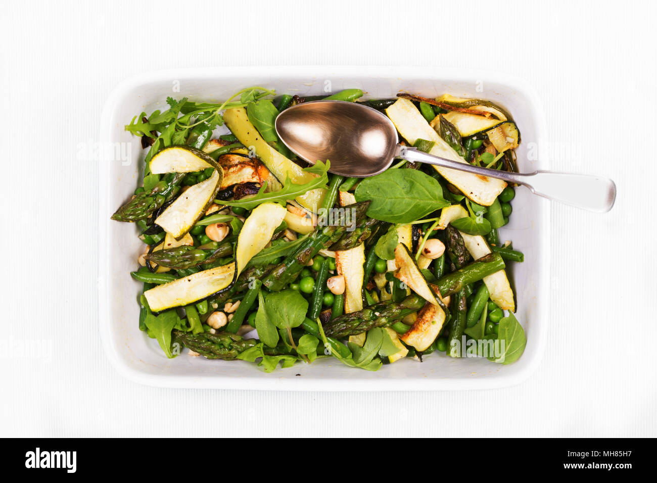 Asparagi, la zucchina e nocciola insalata in un piatto di forma rettangolare con un cucchiaio su un tovagliolo bianco. Vista da sopra Foto Stock