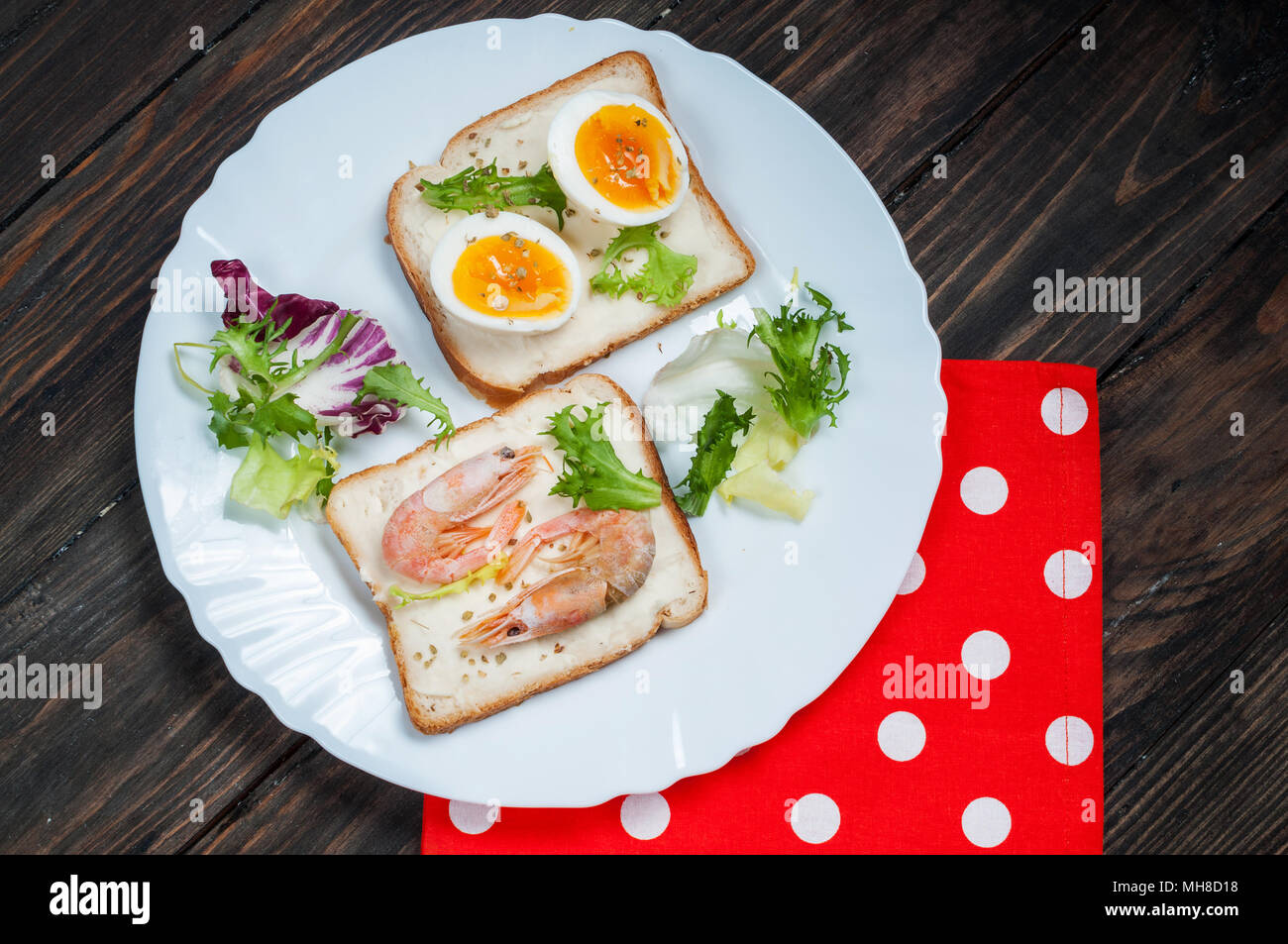 Panini con gamberetti, uovo, basilico, insalata, pane su uno sfondo di legno. Deliziosi spuntini freddi. Pasti vegetariani. Mangiare sano. Foto Stock