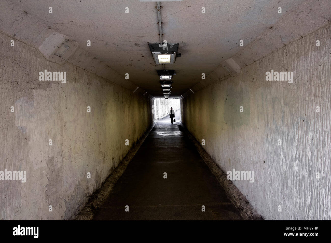 Una figura a piedi attraverso un buio e cupo sottopassaggio in truro City Centre in Cornovaglia. Foto Stock