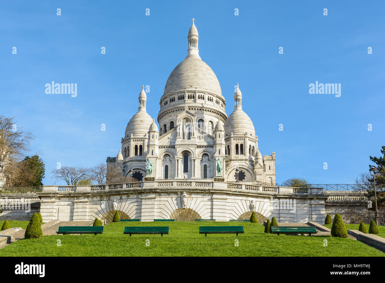 Vista frontale della basilica del Sacro Cuore di Parigi in cima alla collina di Montmartre visto da Louise Michel parco in una soleggiata mattina di primavera. Foto Stock