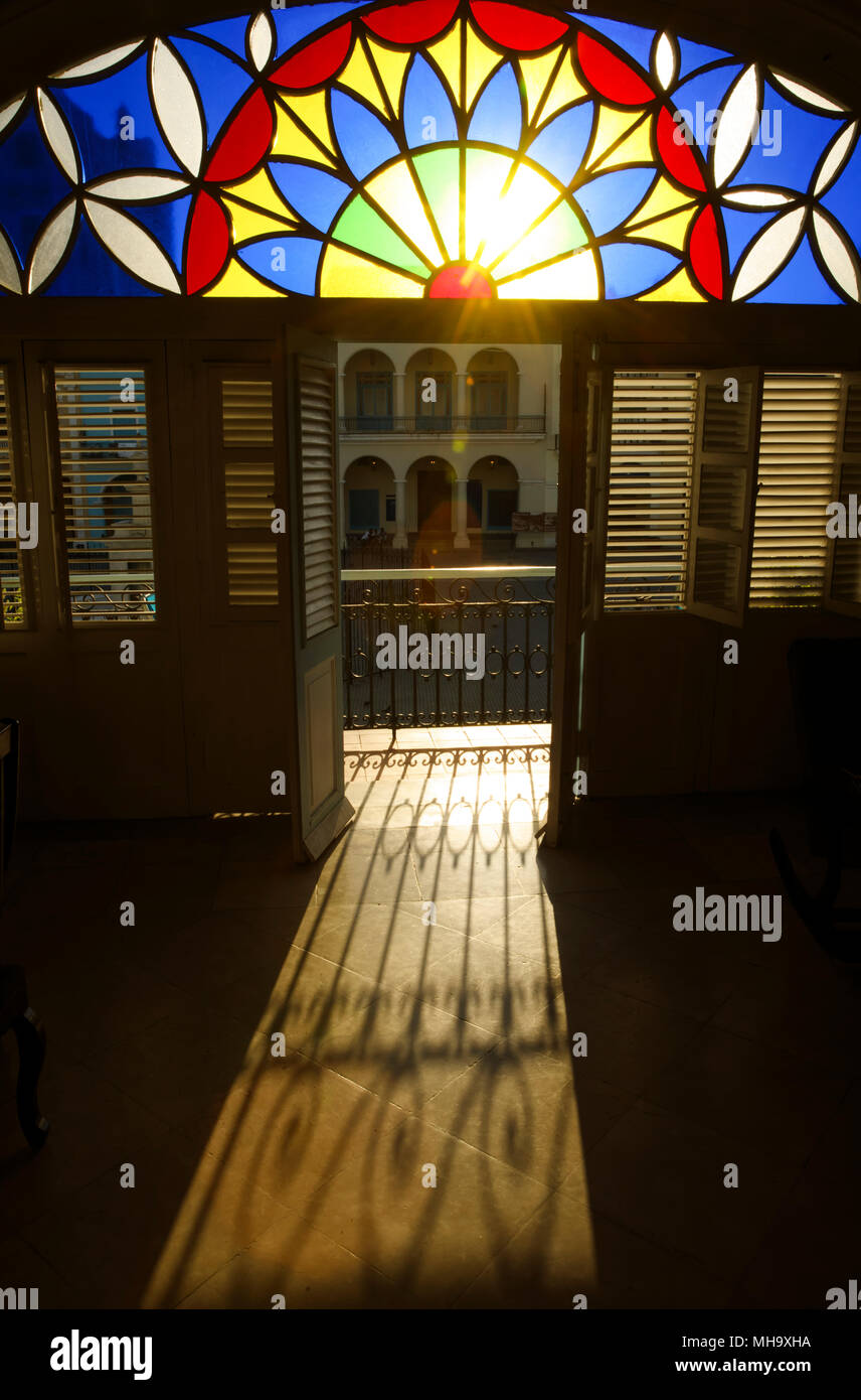 Il sole del mattino splende attraverso il vetro macchiato e una porta aperta di una casa particular su Plaza Vieja a l'Avana, Cuba. Foto Stock