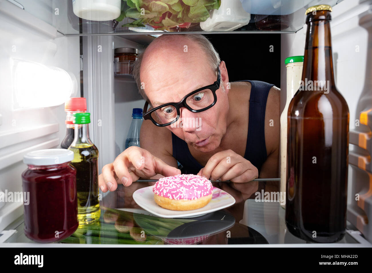 L uomo alla scoperta di una ciambella in frigo Foto Stock