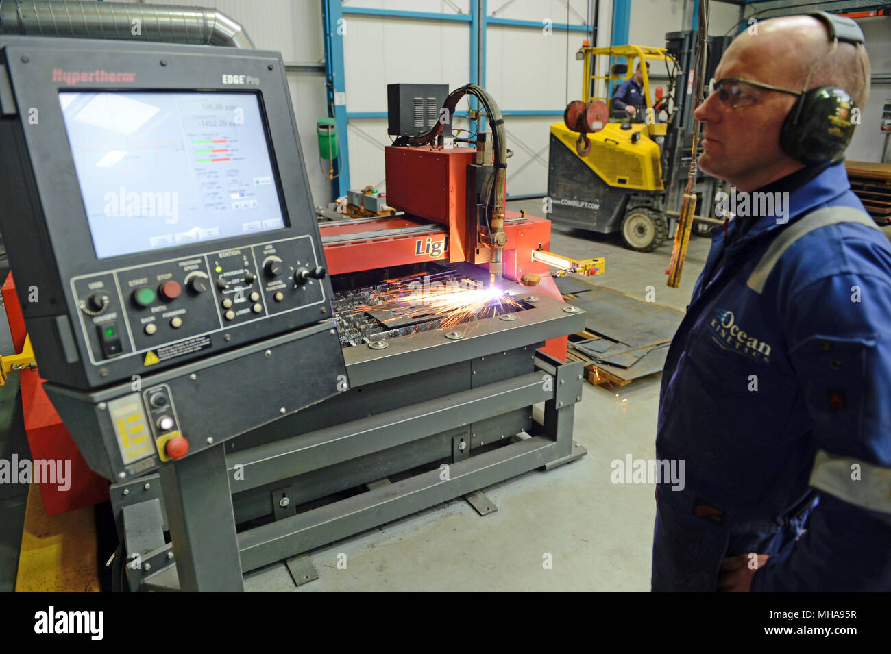 Uomo al lavoro su un metallo di plasma macchina di taglio in un'officina meccanica Foto Stock