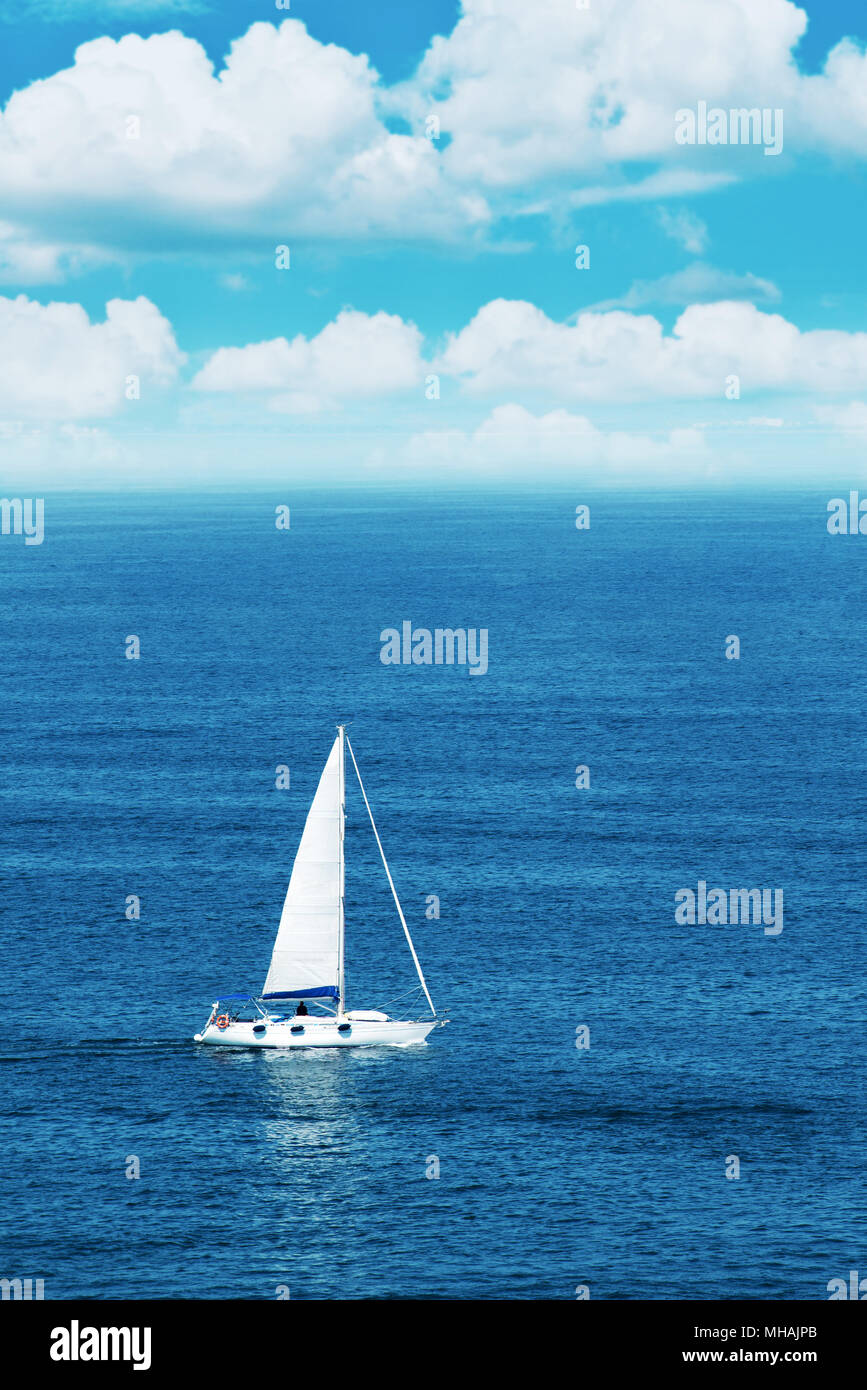 Una barca a vela sul mare aperto, nuvole all'orizzonte Foto Stock