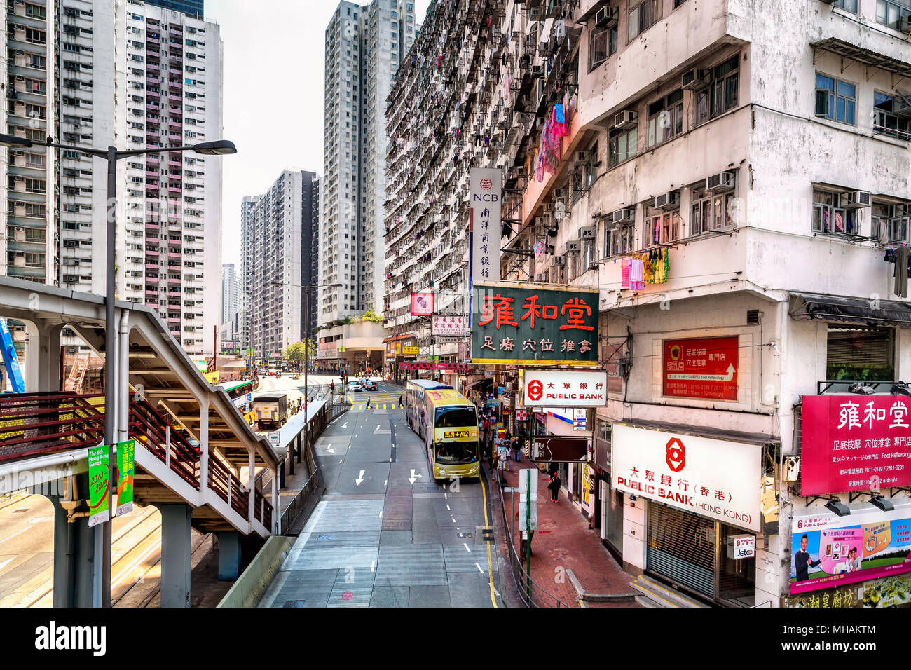 Servizio lavanderia appeso fuori ad asciugare dalle finestre di alto edificio di appartamenti in King's Road, Quarry Bay, Hong Kong Island. Di seguito, il traffico e gli acquirenti si mescolano. Foto Stock