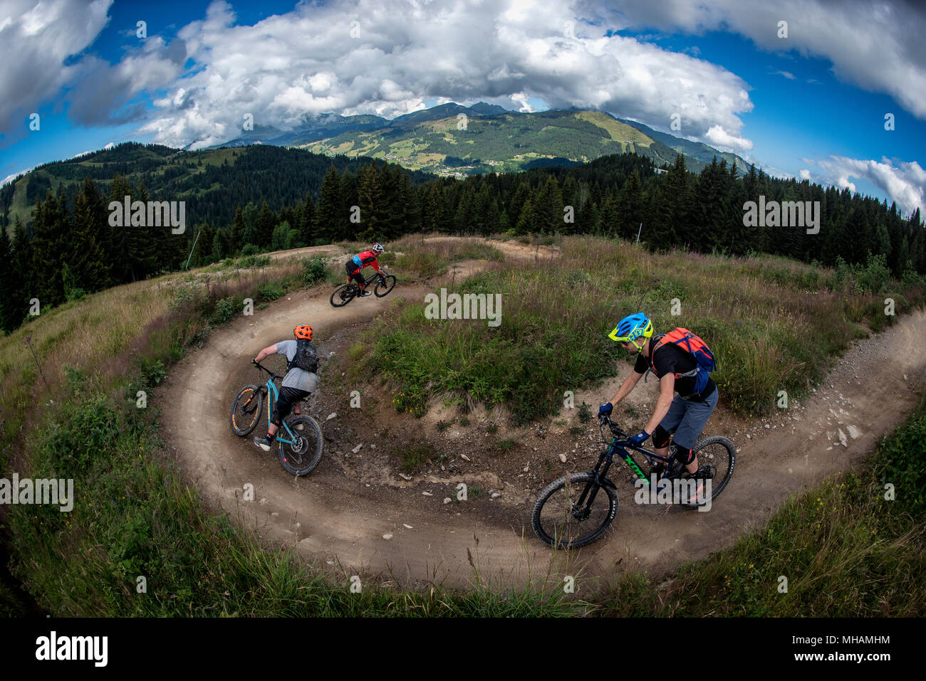 Tre i ciclisti di montagna cavalcare un uomo fatto trail in Les Gets bikepark in Portes du Soleil ski area nelle Alpi francesi. Foto Stock