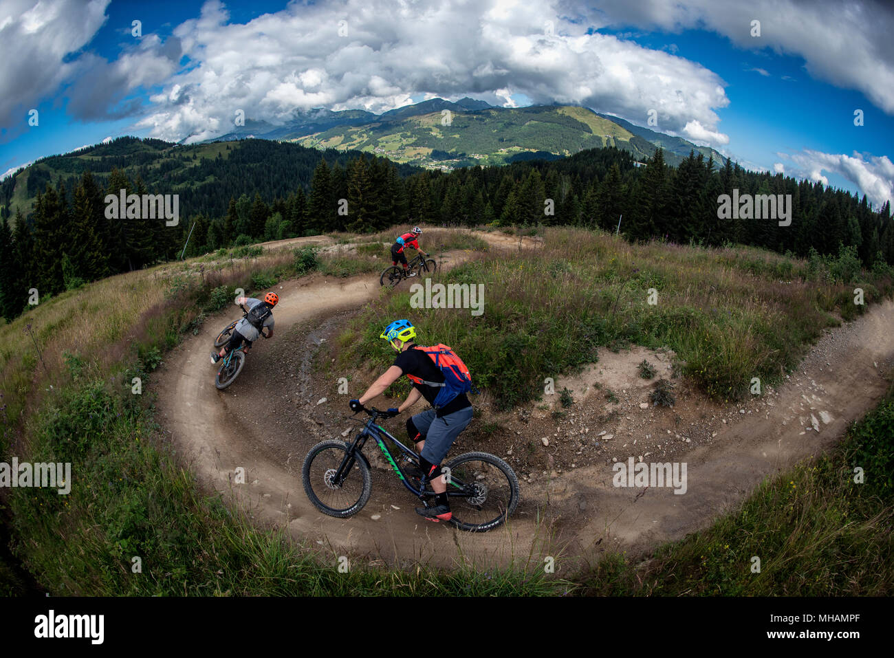 Tre i ciclisti di montagna cavalcare un uomo fatto trail in Les Gets bikepark in Portes du Soleil ski area nelle Alpi francesi. Foto Stock