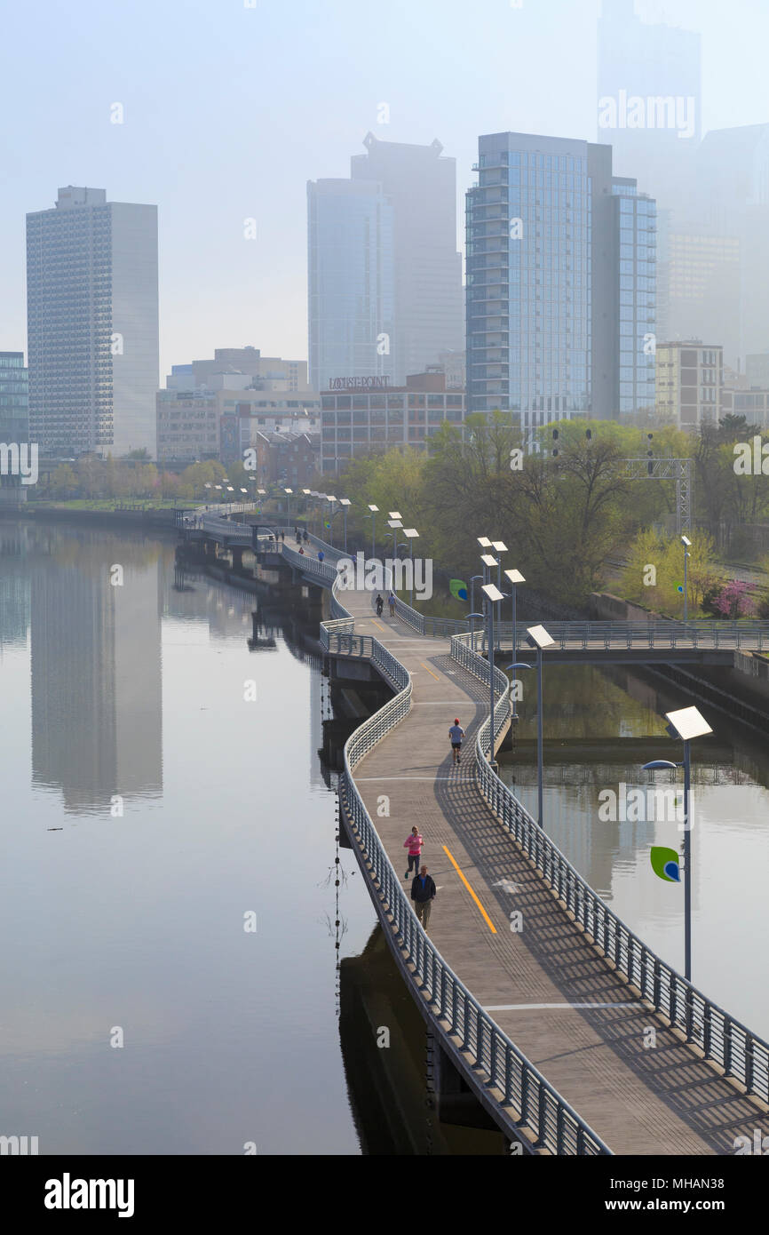 Lo Skyline di Philadelphia con Schuylkill River Park Boardwalk in primavera con gli amanti del jogging e il ciclista, Philadelphia, Pennsylvania, STATI UNITI D'AMERICA Foto Stock