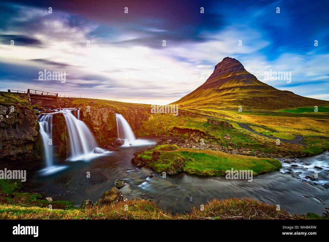 Cascata Kirkjufellsfoss con Kirkjufell mountain in background al tramonto, Islanda Foto Stock