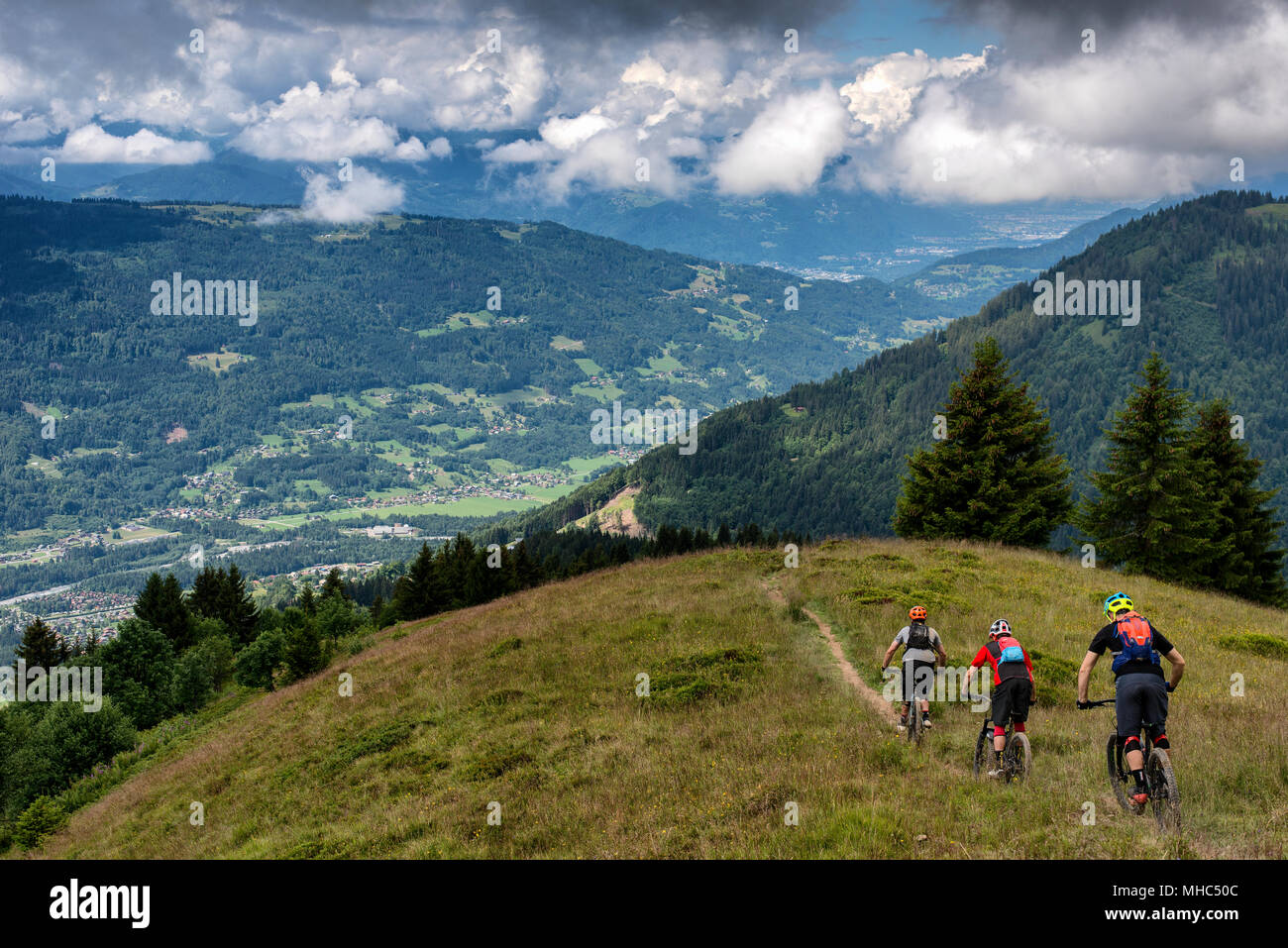 Un gruppo di uomini in mountain bike cavalcare un sentiero lungo una cresta vicino al Col de Joux piano nella direzione del francese città alpina di Samoëns. Foto Stock