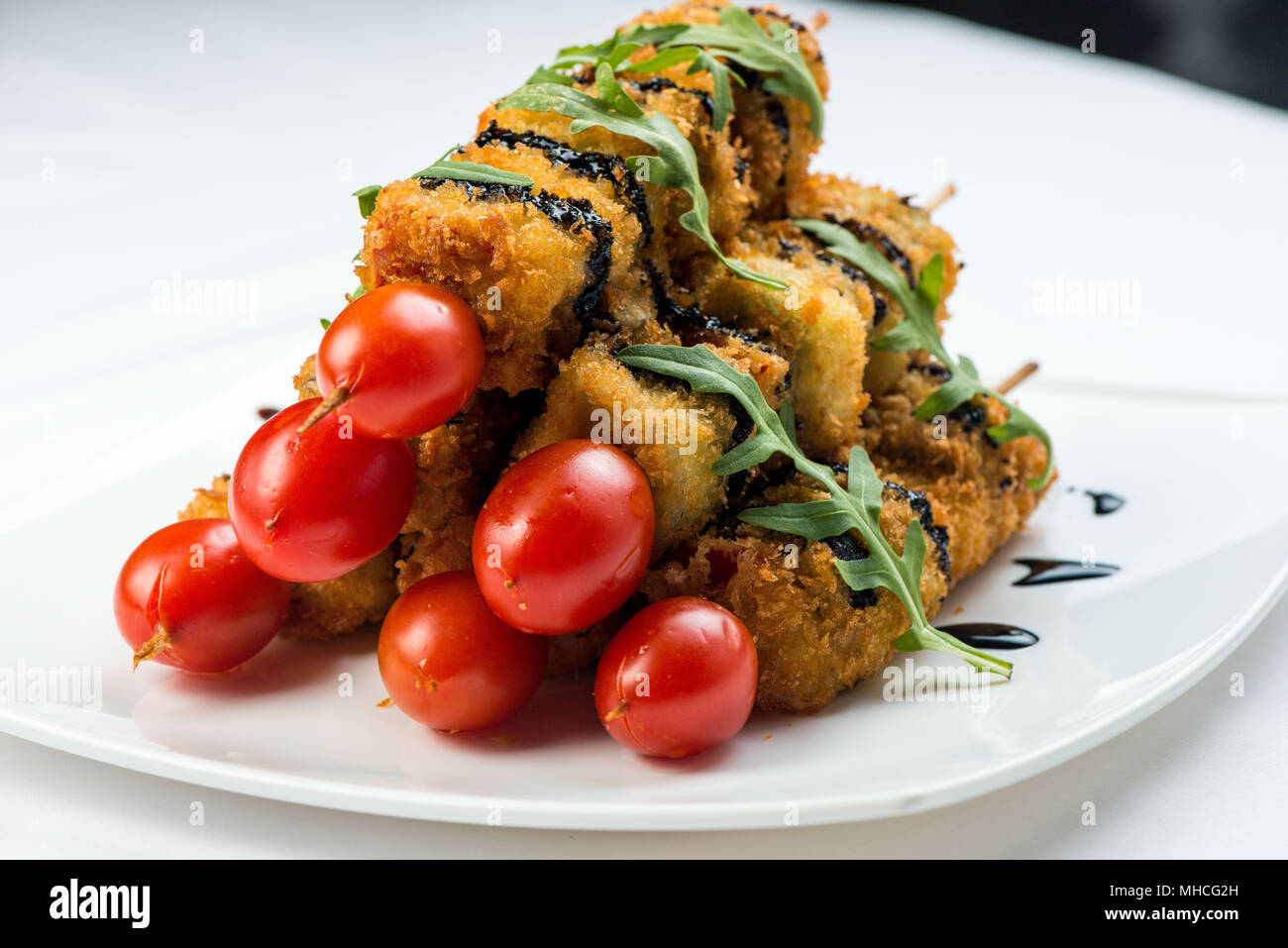 Verdure su spiedini fritti in pastella decorate con pomodori, zucchine, melanzane, zucchine. piastra bianca su sfondo bianco Foto Stock