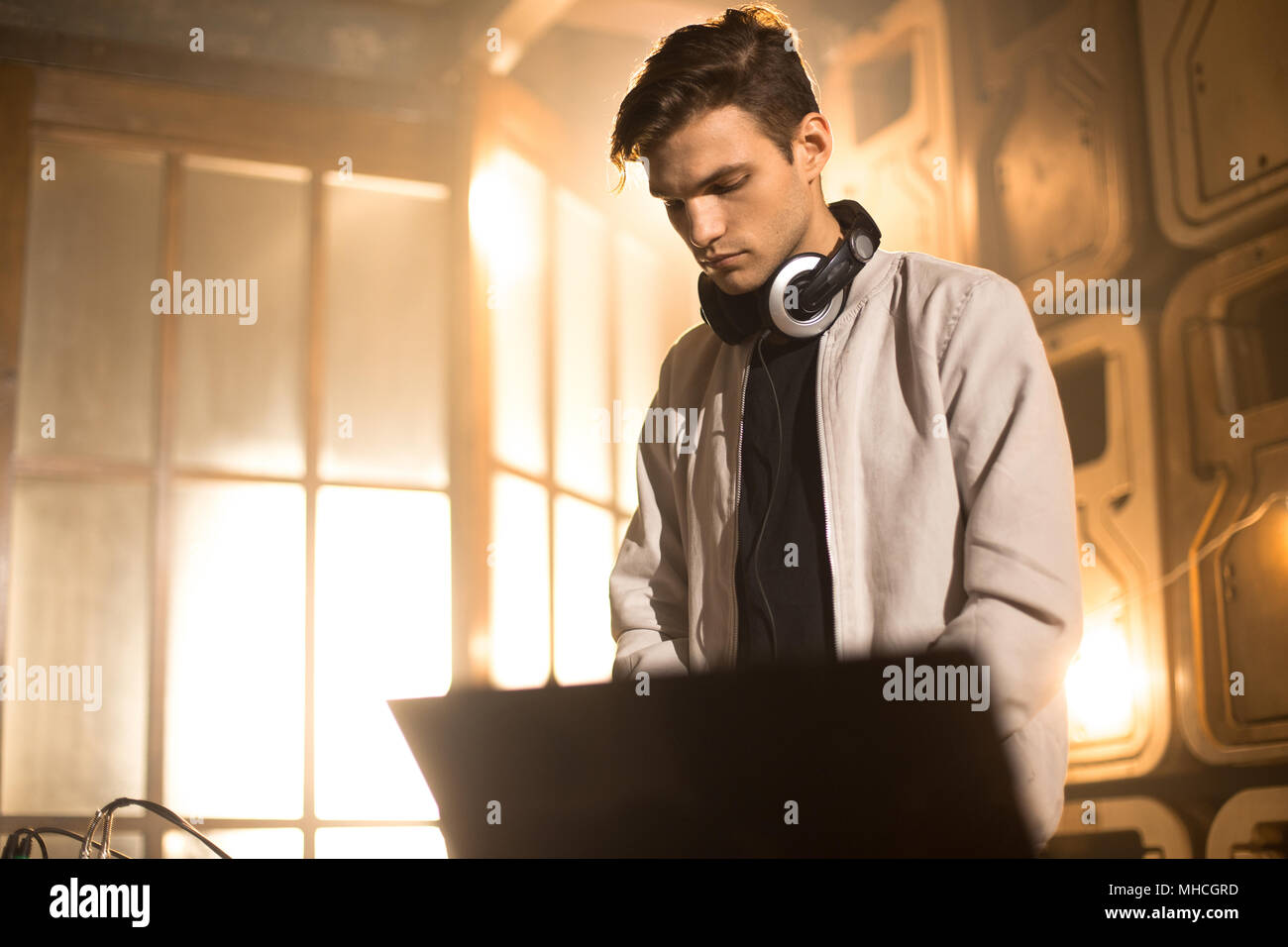 Vita ritratto di moda giovane DJ la riproduzione di musica tramite il miscelatore e guardando lo schermo del notebook in un night club party, spazio di copia Foto Stock