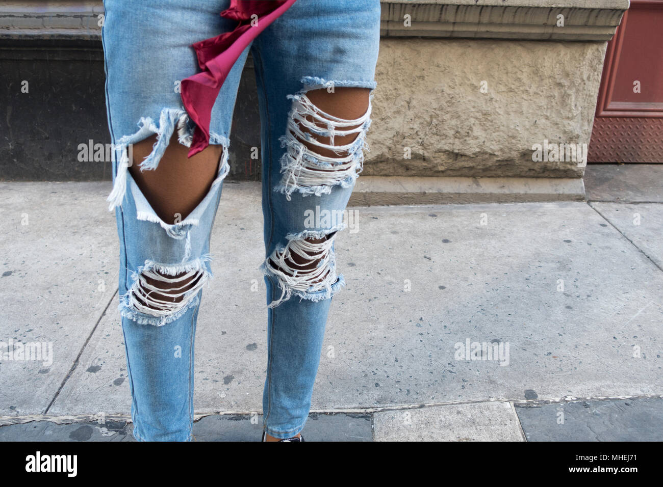 Passerella urbana donna in piedi con distressed grunge jeans blu all'aperto Foto Stock