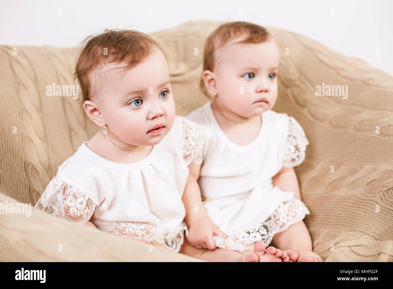 Due adorabili gemelli bambino seduto in poltrona. Foto Stock