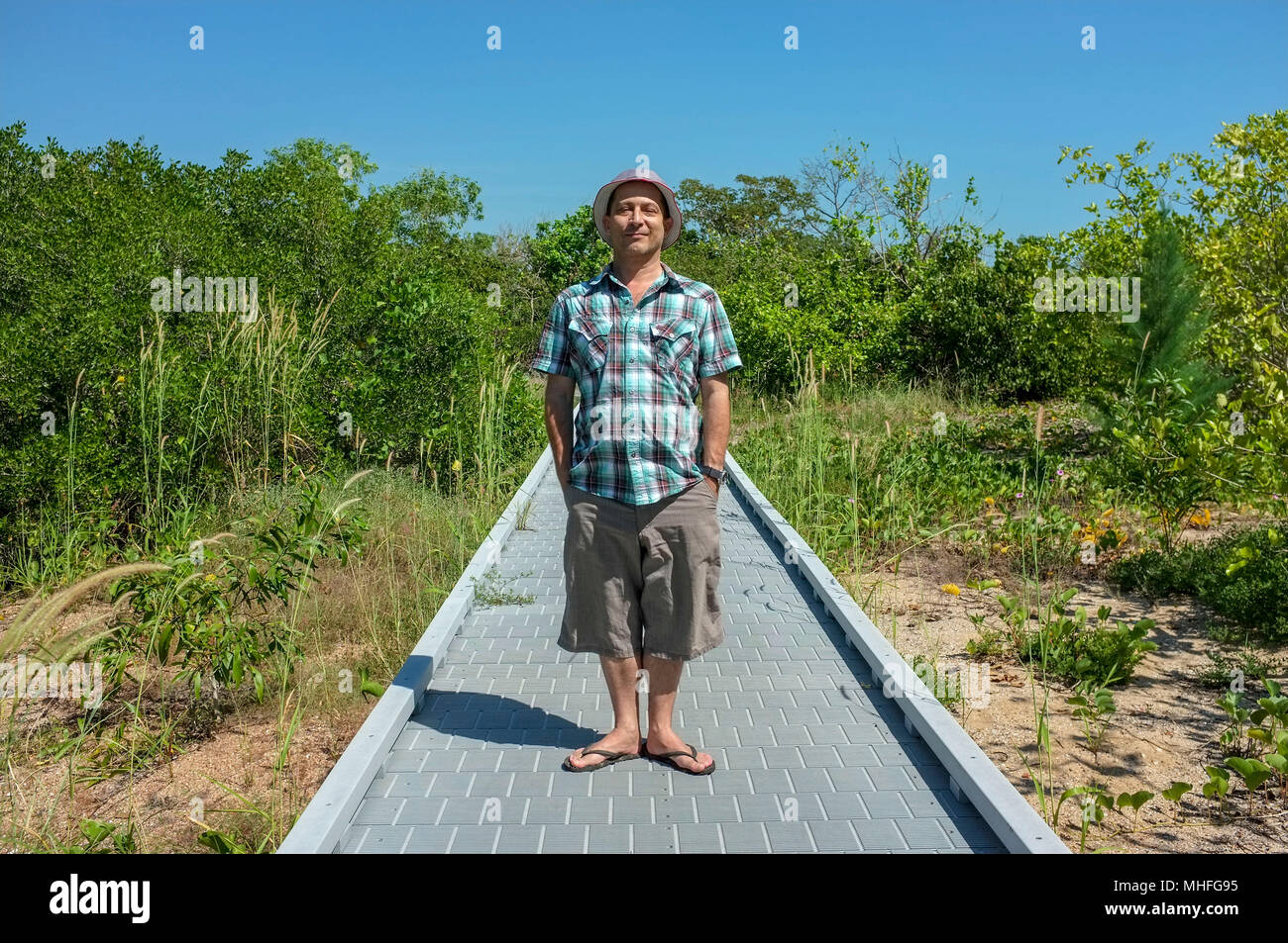 Uomo con le sue mani in tasca in piedi e guardando la telecamera sulla East Point Reserve Mangrove Boardwalk a Darwin, in Australia. Foto Stock