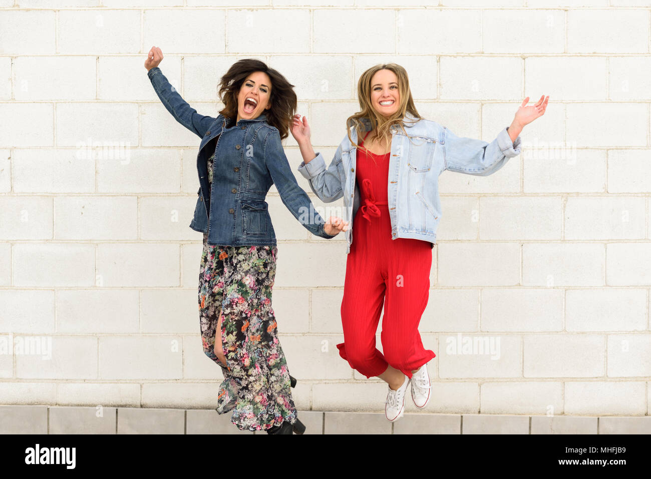Due giovani felici donne saltando in background urbano. Simpatici amici. Il concetto di stile di vita. Foto Stock