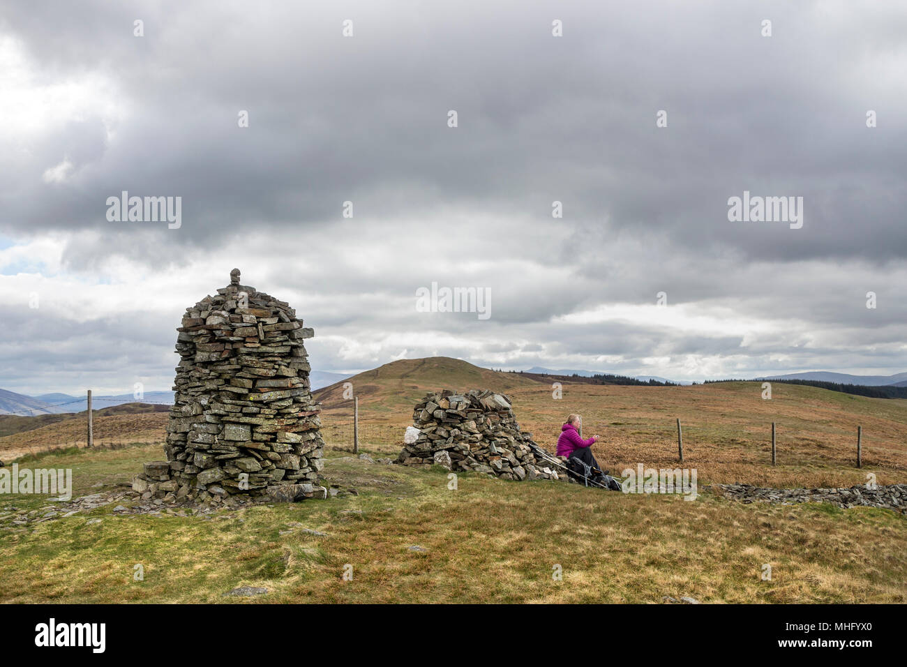 Walker prendendo una pausa sul Vertice di Ginestra è sceso, con la vista verso il Lords sedile, Lake District, Cumbria, Regno Unito Foto Stock