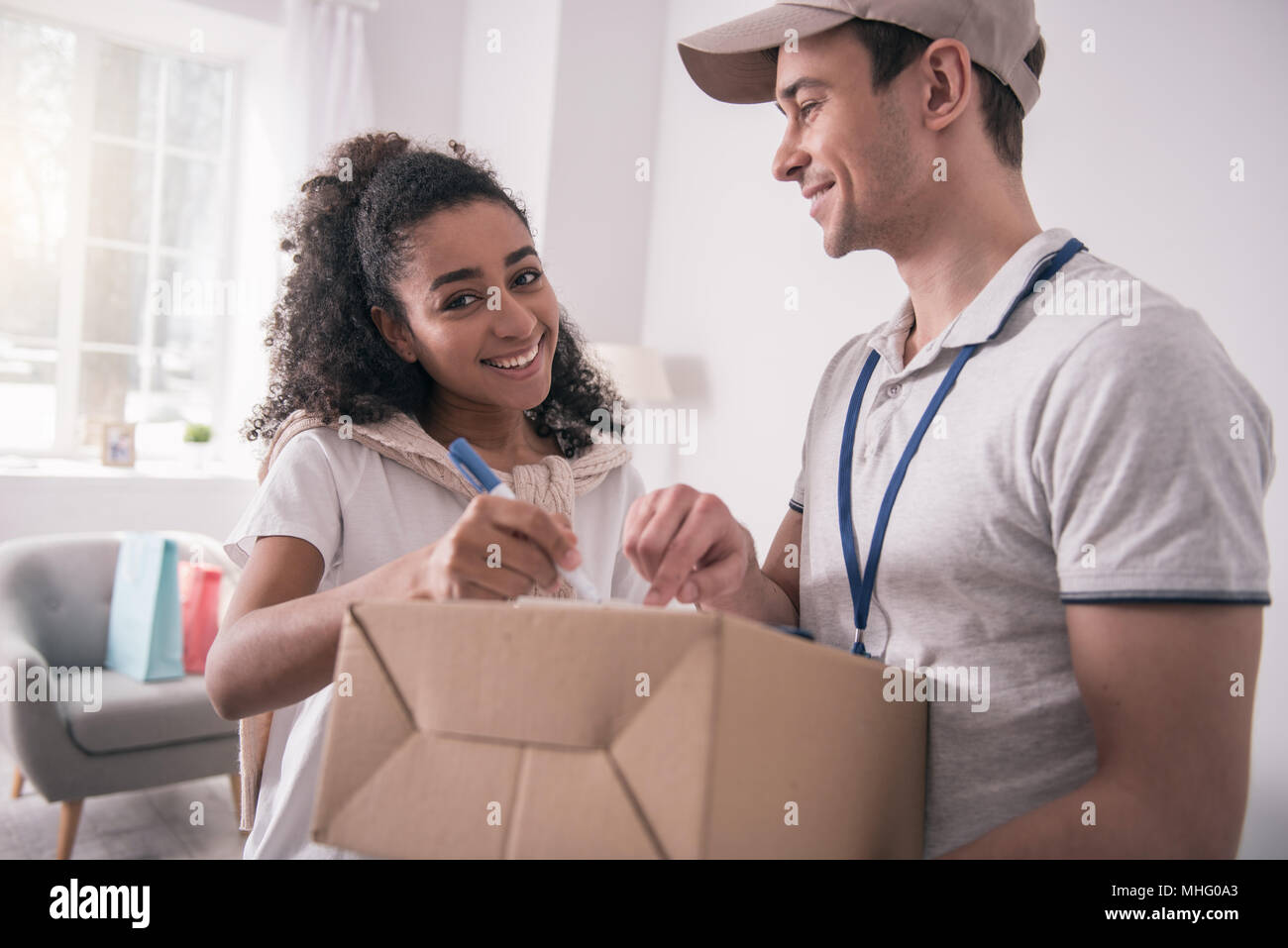 Gioioso guardando bene donna in piedi accanto all'uomo di consegna Foto Stock