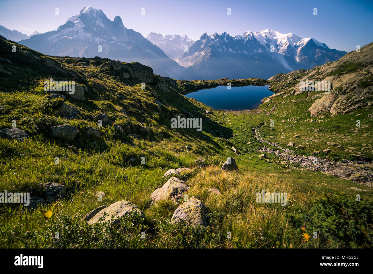 Altitudine lago di montagna e cime innevate su una soleggiata giornata estiva Foto Stock